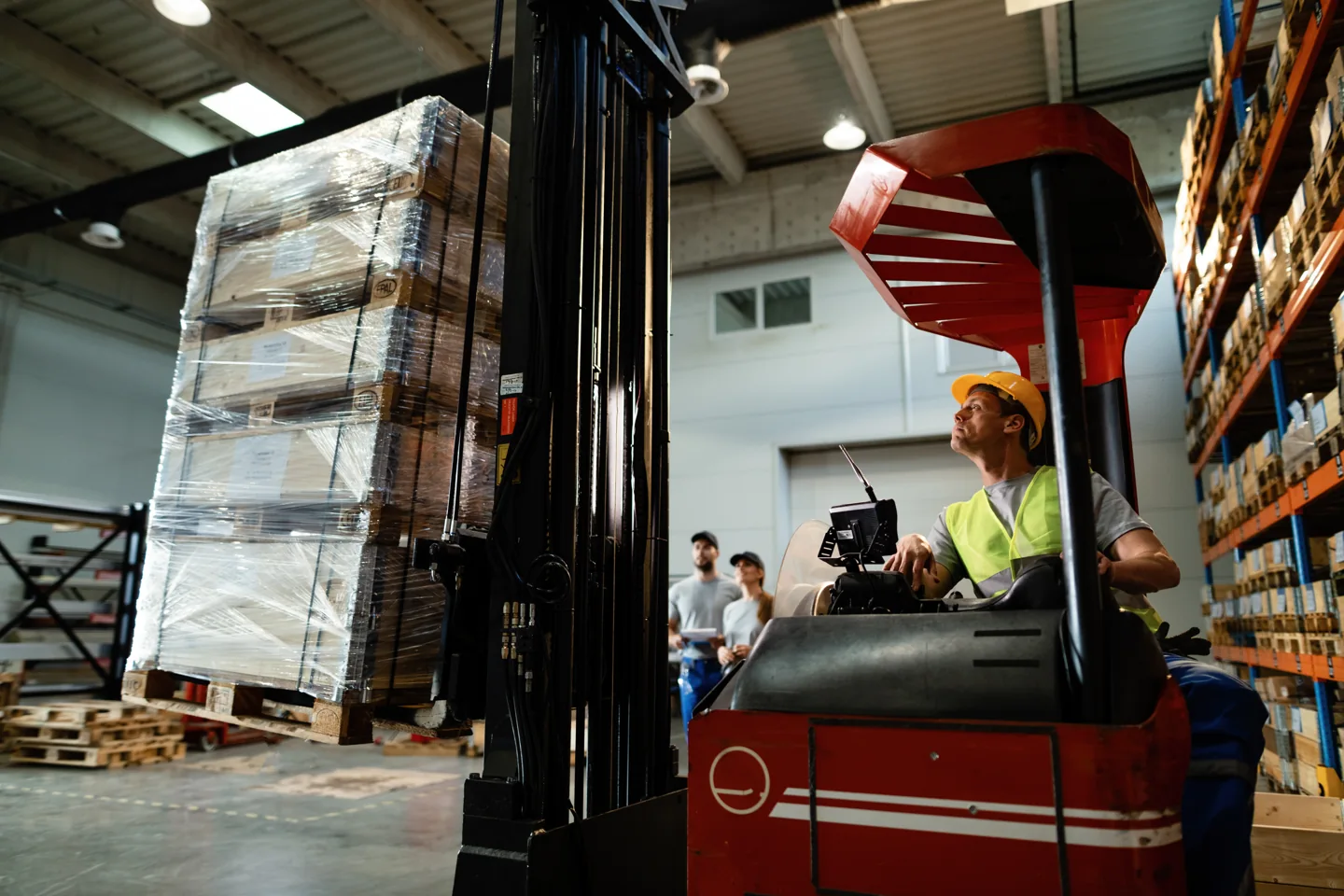 Stock photograph of a forklift operator moving a wrapped pallet in a warehouse