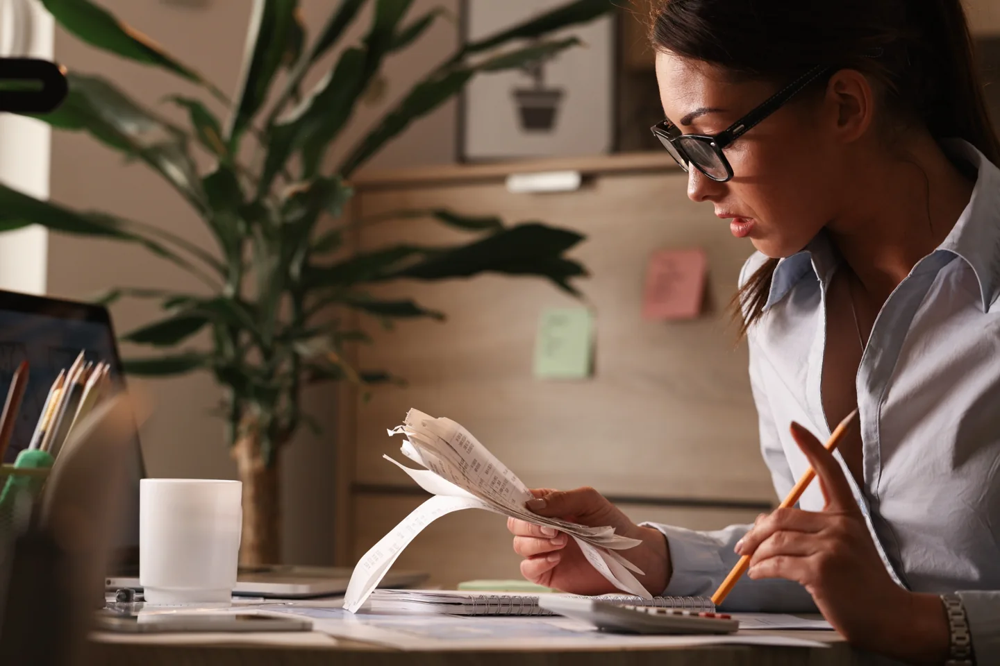 Stock photograph of an accountant reviewing paper bills and writing at a desk