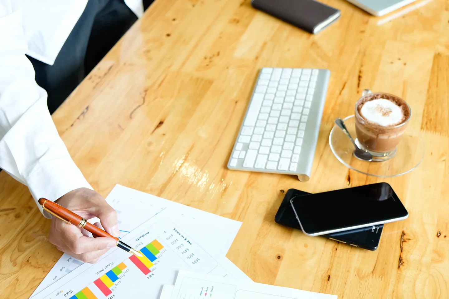 Stock photograph of hands reviewing printed financial charts at a desk