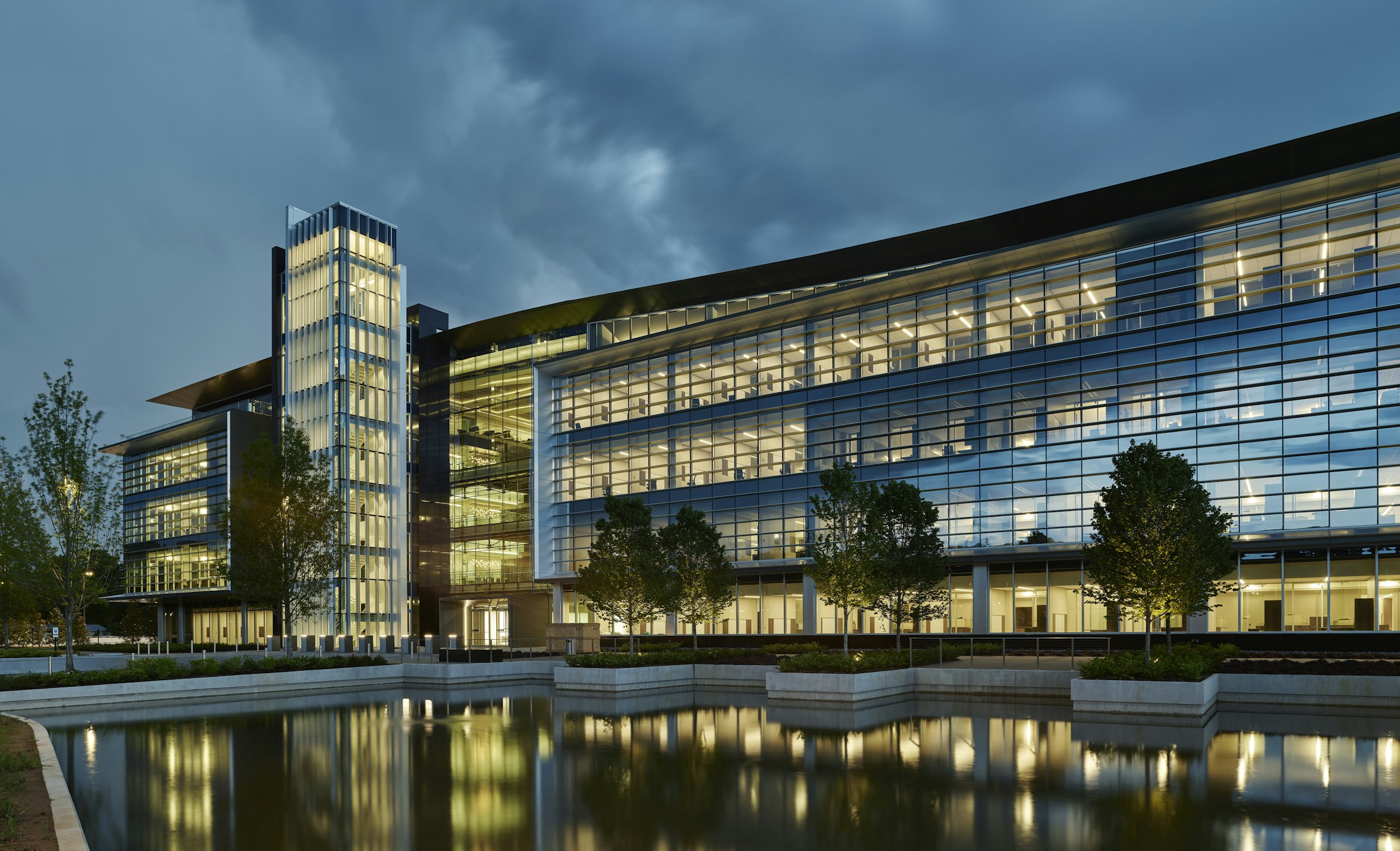 Modern glass office headquarters of Bank OZK illuminated at dusk