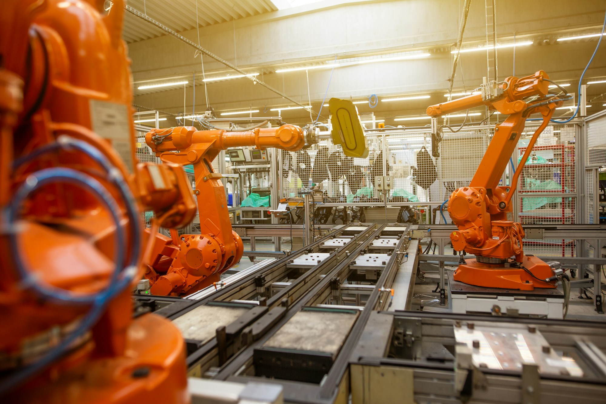 Orange industrial robotic arms operating on an automated factory assembly line